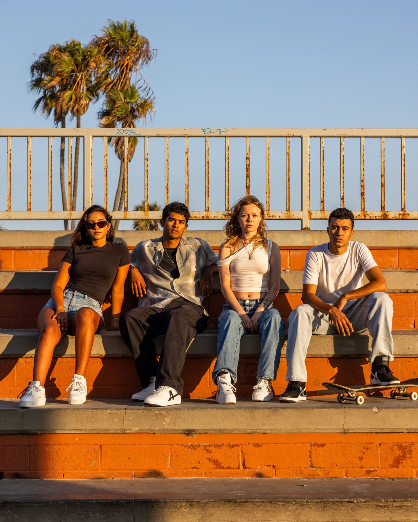 Four friends sitting on orange steps in the evening sun